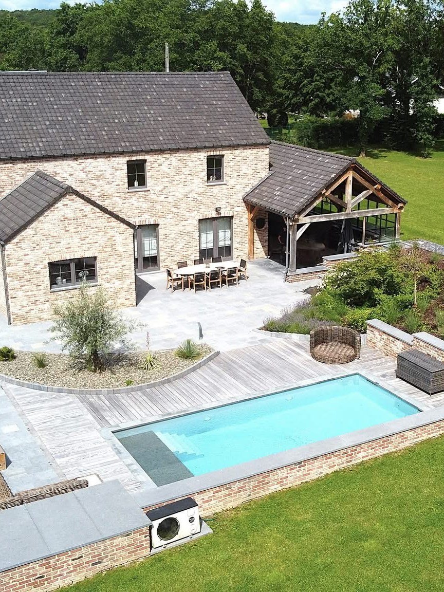 Piscine creusée et terrasse au pied d'une maison en briques
