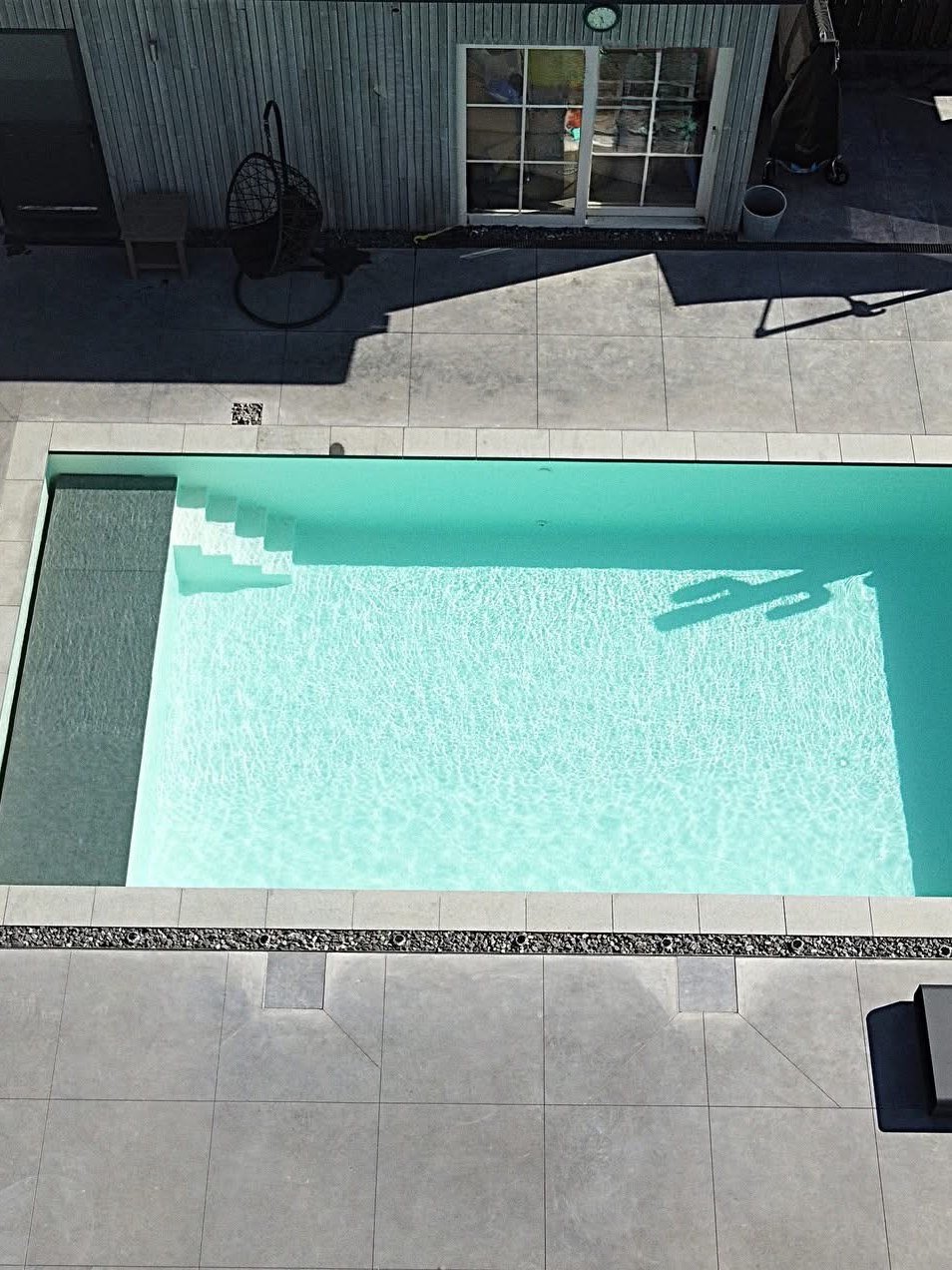 Piscine creusée rectangulaire avec plage carrelée et pool house